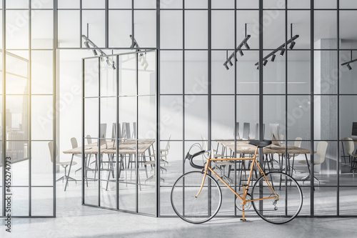 Modern glass partition and bike in stylish coworking office interior with city view and daylight. 3D Rendering.