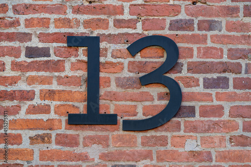 House number thirteen (13) on a red brick wall