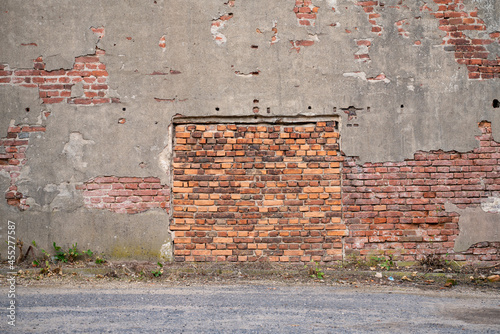 A former entrance in a damaged wall of an unused military fort, walled up with bricks.
