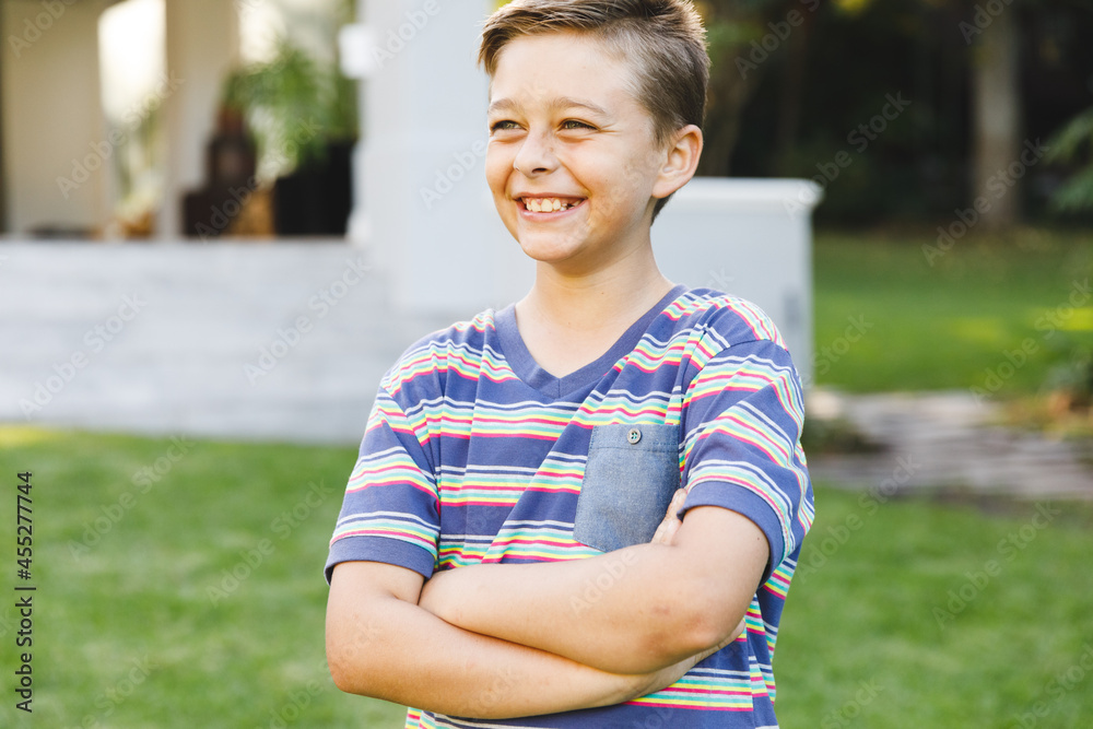 Smiling caucasian boy outside house looking away from camera in garden Smiling caucasian boy outside house looking away from camera in garden