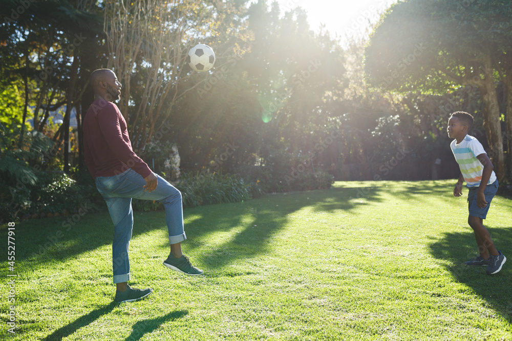 African american father with son having fun and playing football in ...