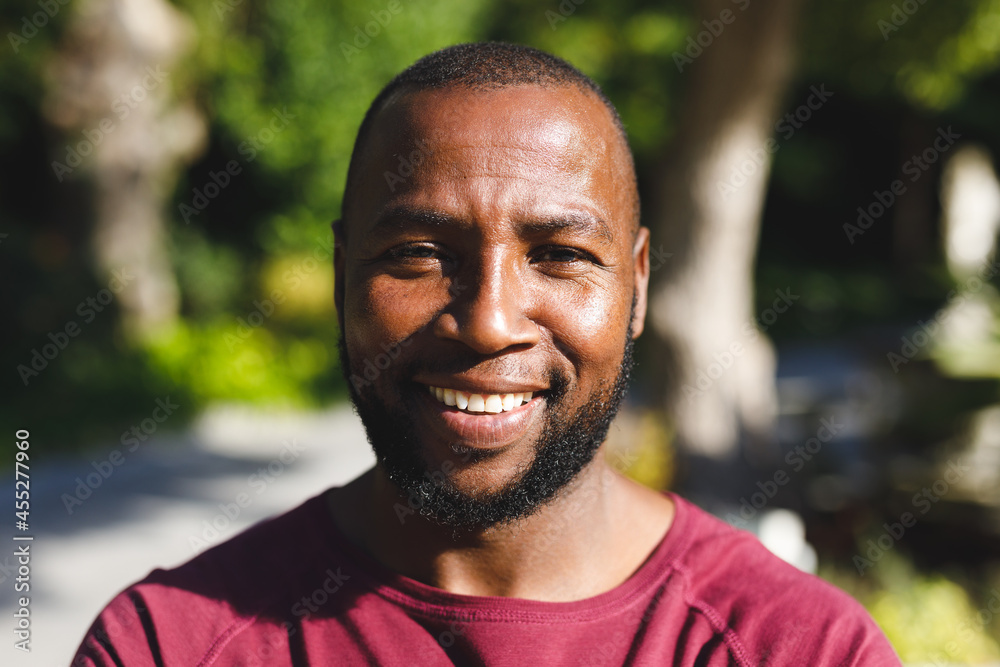 Portrait of african american man smiling and looking at camera in sunny garden Portrait of african american man smiling and looking at camera in sunny garden