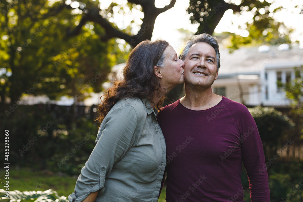 Happy senior caucasian couple kissing and smiling in garden