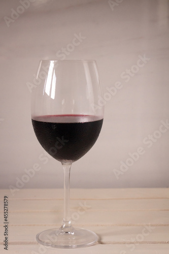 Crystal goblet containing red wine on a neutral white background. Available space to write.