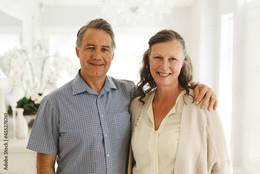 Portrait of happy senior caucasian couple in living room, embracing and smiling Portrait of happy senior caucasian couple in living room, embracing and smiling