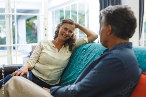 Happy senior caucasian couple in living room sitting on sofa, talking