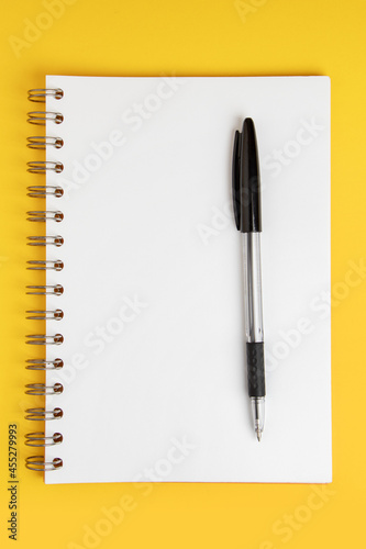 Blank note paper with pen on yellow background