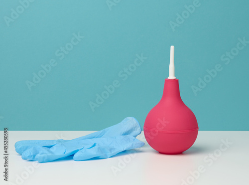 Cuadro en lienzo pink rubber enema on white table, medical instrument for cleaning the body, blue