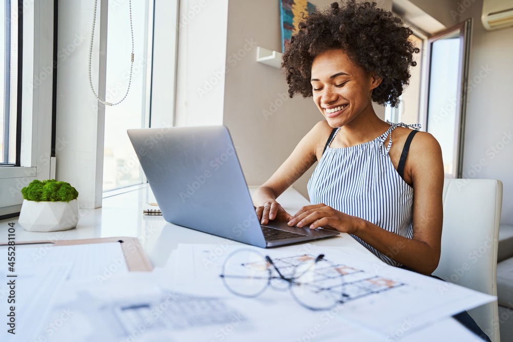 High-spirited dark-haired woman typing on her laptop High-spirited dark-haired woman typing on her laptop