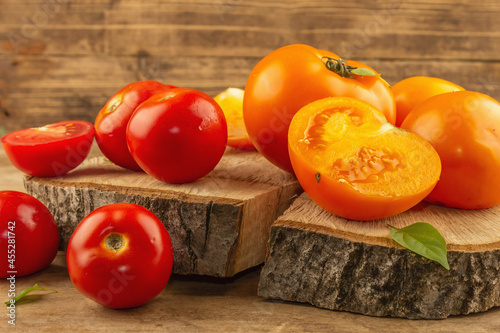 Assorted ripe tomatoes on a wooden stand. Fresh red and orange organic vegetables