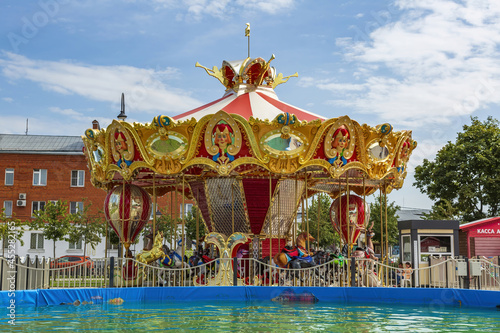 Bright carousel and summer pool in the amusement park on Zhitnaya square. Kolomna, Russia photo