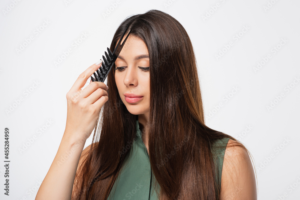 young woman doing hair parting with comb isolated on grey young woman doing hair parting with comb isolated on grey