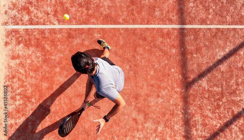 Top view of a paddle tennis player who is hitting the ball on an outdoor court. © REC Stock Footage