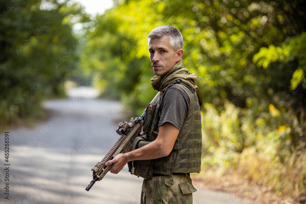 A man standing with an airsoft assault rifle in military uniform