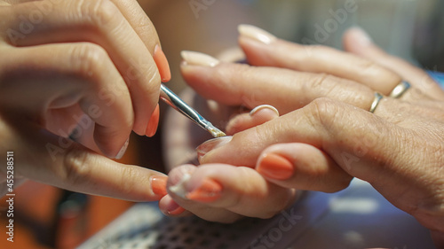 Manicure procedure. Applying nail polish in nail salons. Concept of beauty treatment  femininity  fashion and beauty products.