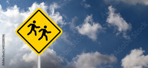 Slow down, school children playing. road sign on blue Sky. Traffic yellow rhombus  signs board. Stop warning caution signal icon. Kids or child play zone or area pictogram.  photo