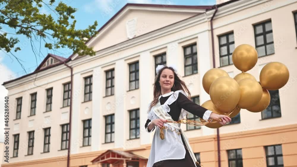 Happy Russian schoolgirl with balloons on graduation day.