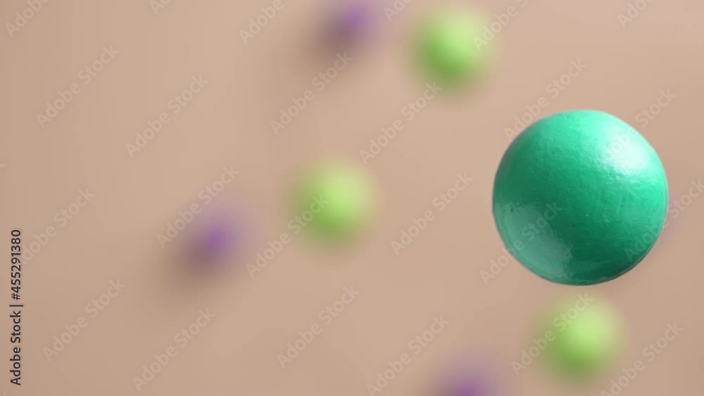 Green and purple balls are moving on a pink background, 3D effect. Bright abstract background with spherical shapes. Green and purple balls are moving on a pink background, 3D effect. Bright abstract background with spherical shapes.