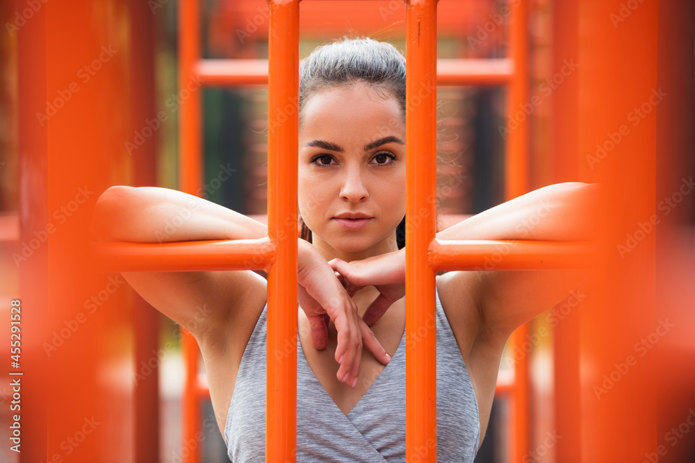 fit woman in sportswear looking at camera near orange vertical ladder outside