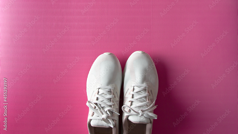 Female sneakers on pink gym mat. Home fitness concept.Copy space Female sneakers on pink gym mat. Home fitness concept.Copy space