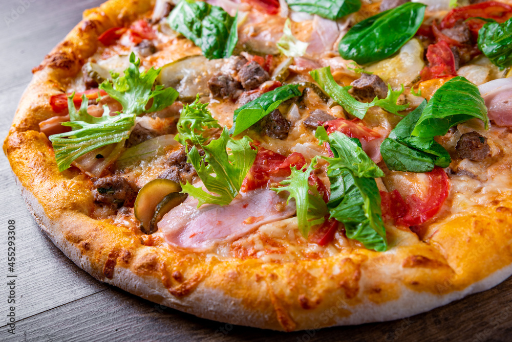Pizza with cheese, Bolognese sauce, minced meat, bacon, tomato and vegetables. Italian pizza on wooden background. Pizza with cheese, Bolognese sauce, minced meat, bacon, tomato and vegetables. Italian pizza on wooden background.