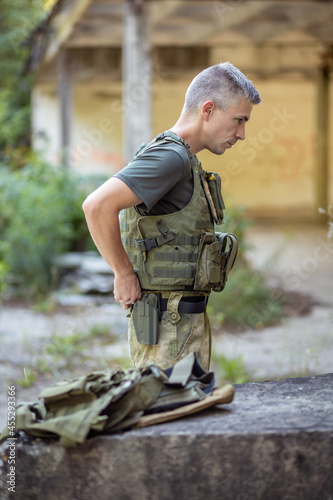 A man preparing for the airsoft game in an abandoned hangar in military uniform