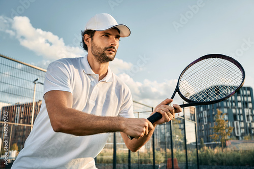 Handsome tennis player with tennis racket while tennis match in motion © Peakstock