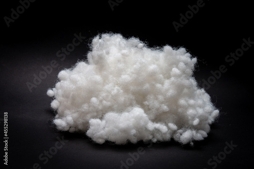 Synthetic fiber, siliconized holofiber, polyester fiber, white synthetic winterizer on a black background. It is used as a filler for blankets, pillows, clothes and upholstered furniture. Close-up.