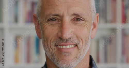 Close up portrait mature man smiling in fornt of bookshelf photo