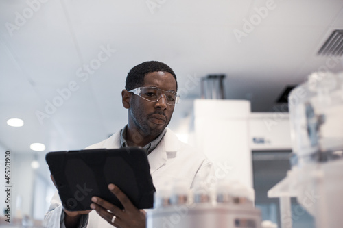 African American male scientist recording data on a digital tablet in a laboratory photo