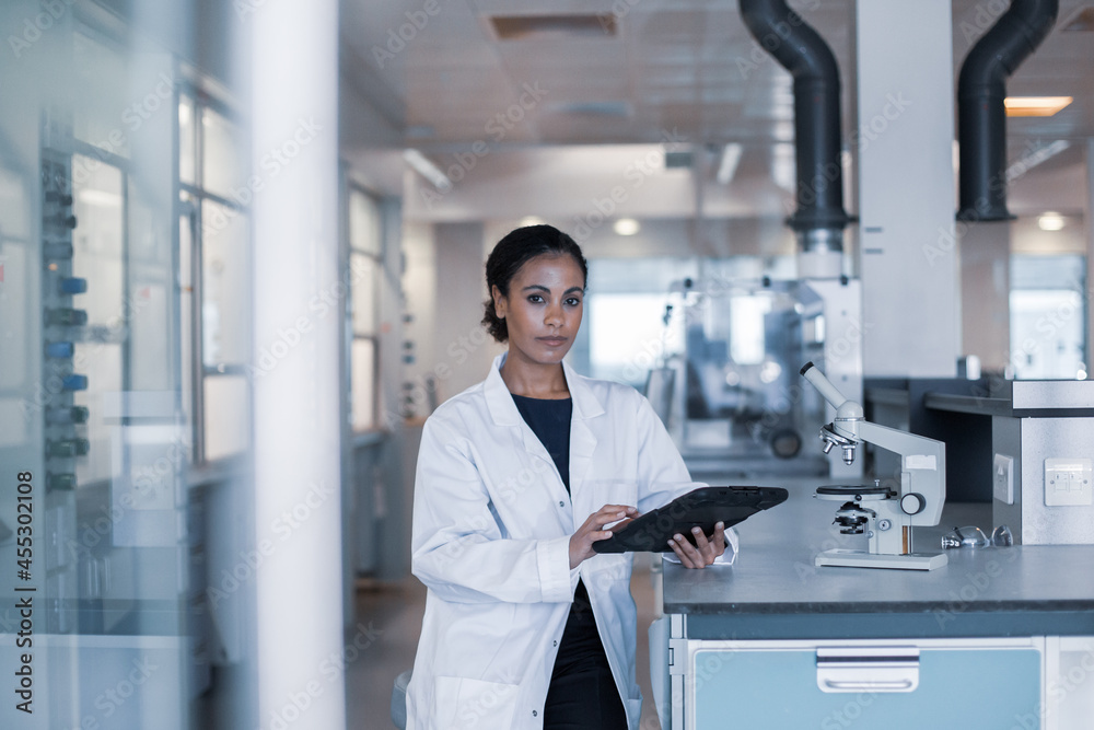 African American female scientist looking at results of experiment on a digital tablet African American female scientist looking at results of experiment on a digital tablet