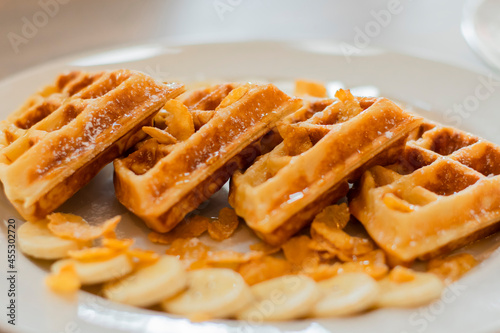 Waffles in a plate, with banana and caramel sauce.