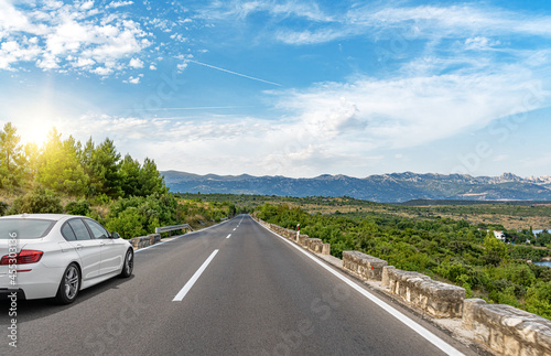 White car on a scenic road. Car on the road surrounded by a magnificent natural landscape. © Denis Rozhnovsky