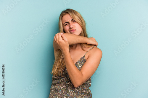 Young caucasian blonde woman isolated on blue background having a neck pain due to stress, massaging and touching it with hand.