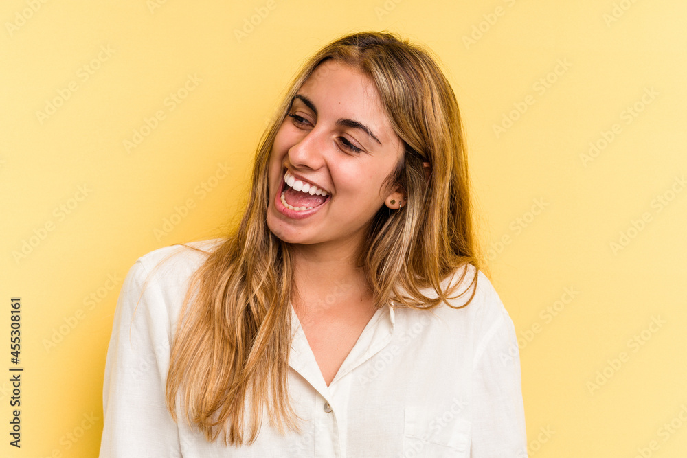 Young caucasian blonde woman isolated on yellow background laughs and closes eyes, feels relaxed and happy. Young caucasian blonde woman isolated on yellow background laughs and closes eyes, feels relaxed and happy.