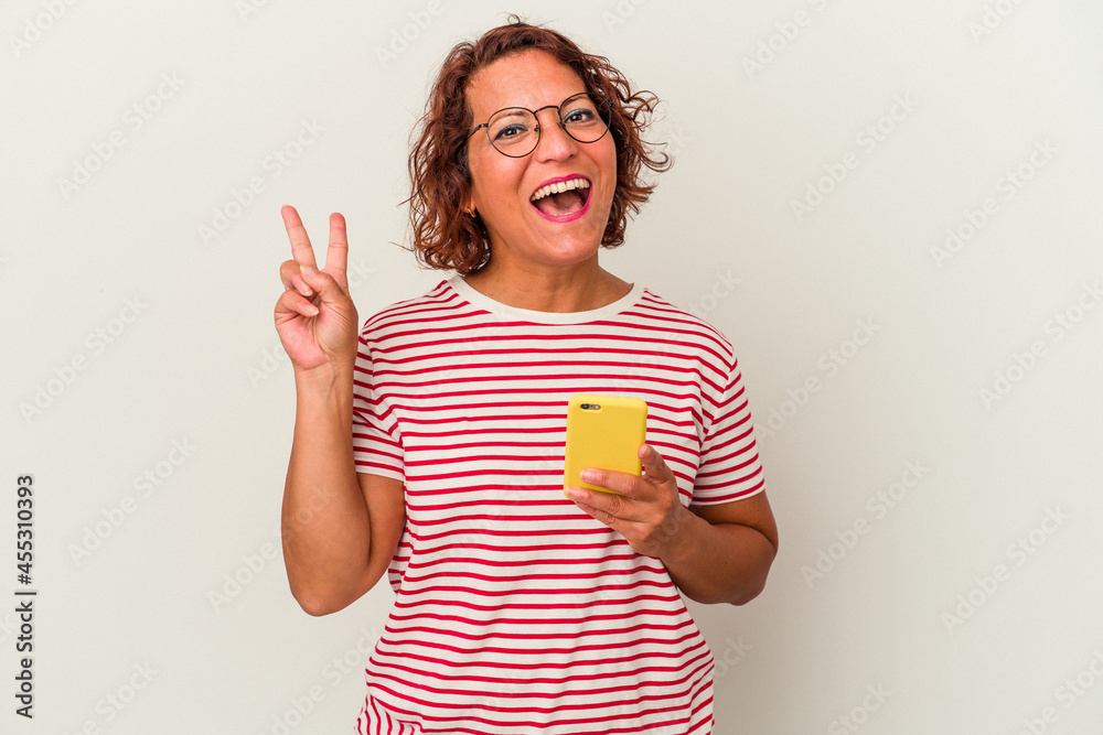 Middle age latin woman isolated on white background joyful and carefree showing a peace symbol with fingers.