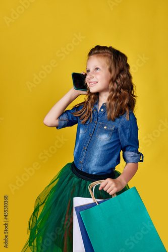 child girl holds shopping bags and using smart phone photo