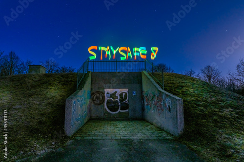 Best wishes in times of Corona and the Covid-19 virus, lightpaining at night with STAY SAFE painted colorful at the top of a bunker. photo