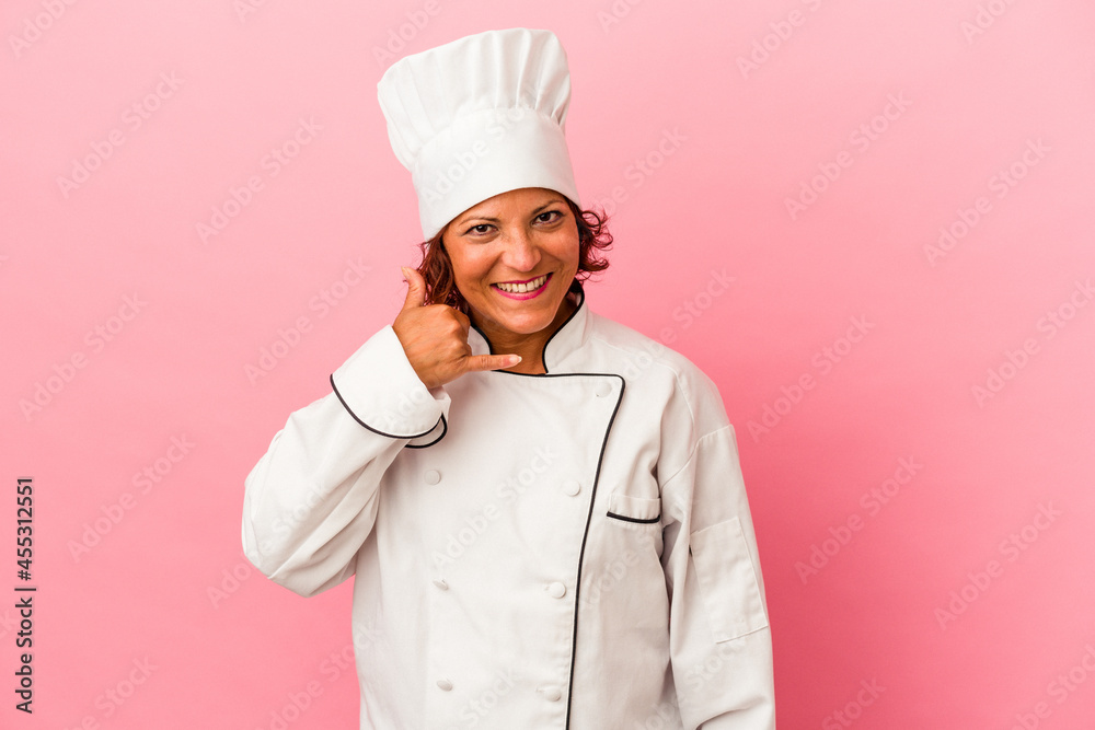 Middle age latin woman isolated on pink background showing a mobile phone call gesture with fingers. Middle age latin woman isolated on pink background showing a mobile phone call gesture with fingers.