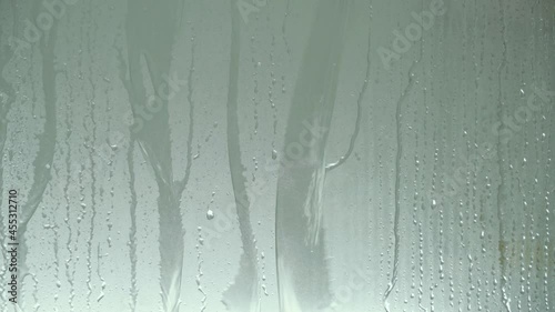 Water drop and droplet flowing down on shower glass