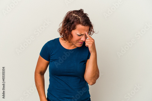 Middle age latin woman isolated on white background having a head ache, touching front of the face.