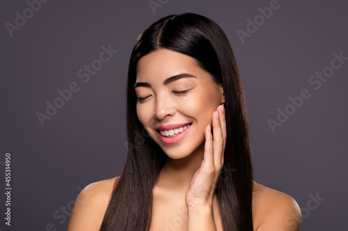 Photo of cheerful dreamy chinese brunette lady hand cheek enjoy silky smooth face skin isolated grey color background