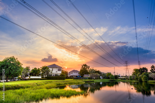 Line of high voltage power with electricity transmission close to residential buildings. Power transmission tower in city with urban area.