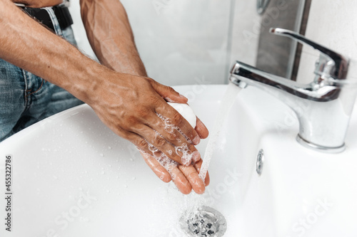 A man washes his hands with soap in the sink, close-up photo