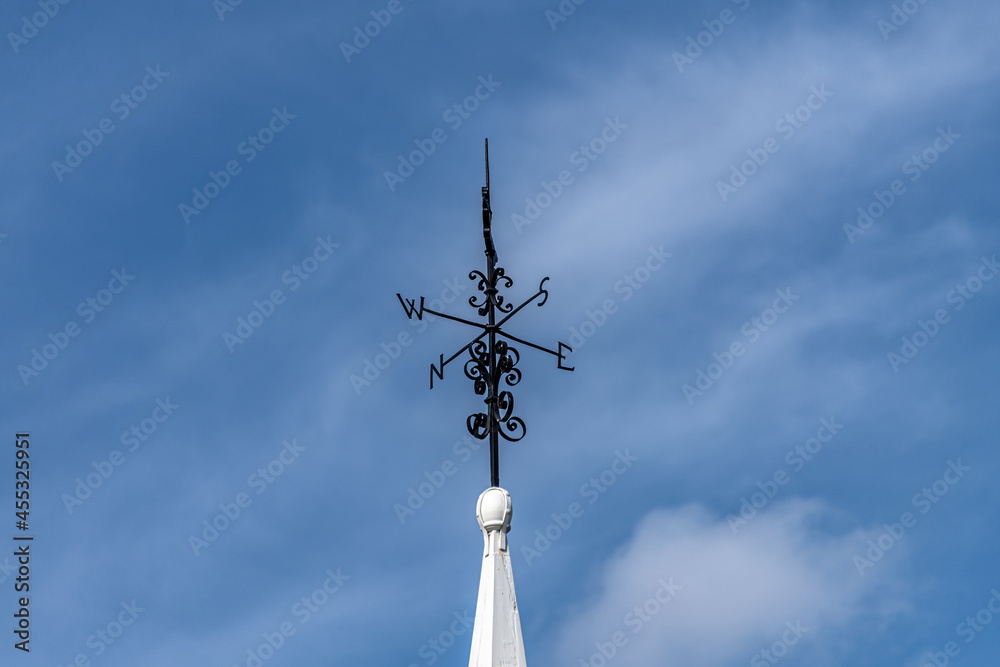 Wind vane with compass and blue sky background Wind vane with compass and blue sky background