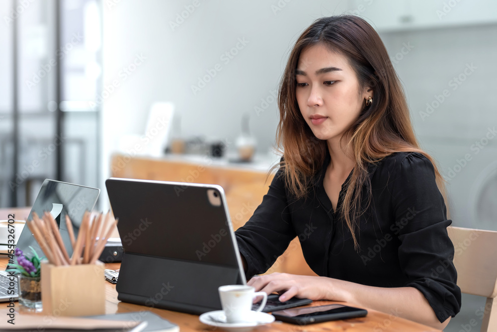 Young Asian businesswoman sitting seriously working using tablet at office. Young Asian businesswoman sitting seriously working using tablet at office.