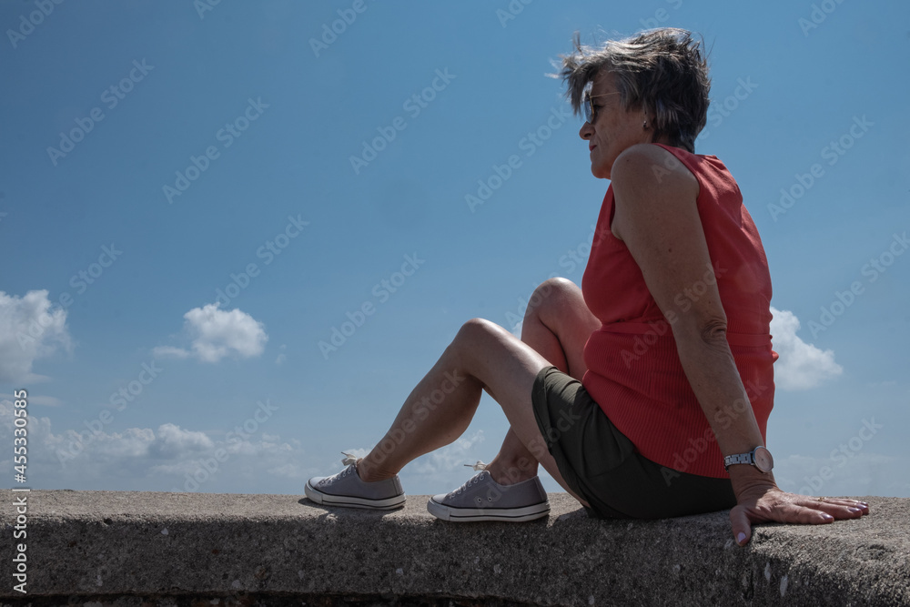 Woman looking down on the valley from a mountain top Woman looking down on the valley from a mountain top