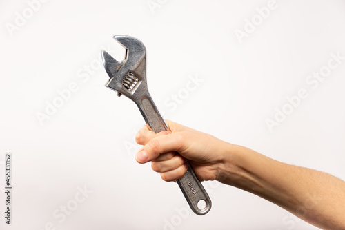 Mano sosteniendo herramienta, llave alemana. Fondo blanco. 