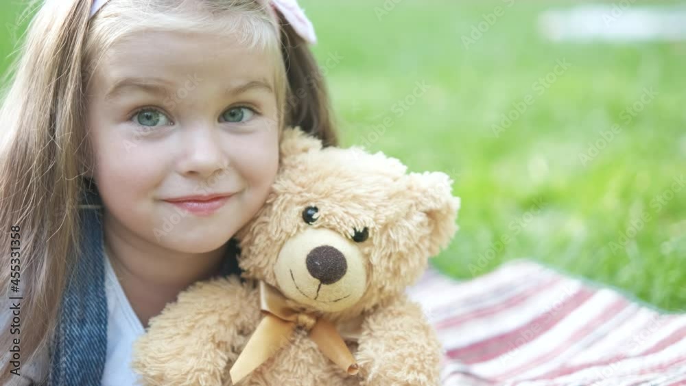 Pretty child girl playing with her favorite teddy bear toy outdoors in summer park. Pretty child girl playing with her favorite teddy bear toy outdoors in summer park.