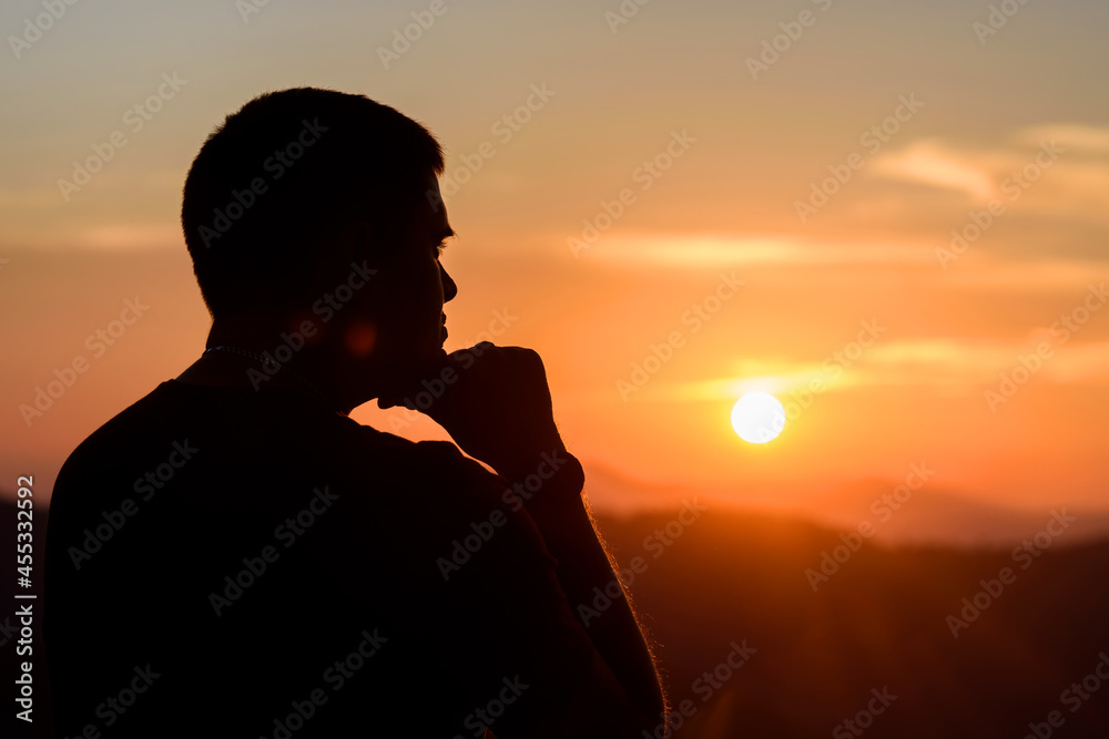 Man with hands on chin stand on the mountain and watching over the misty sunset